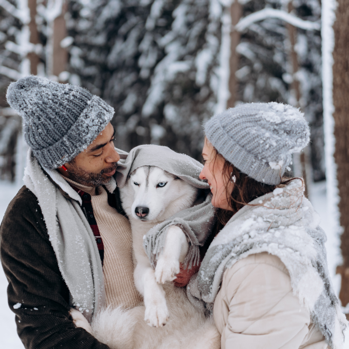 ζευγάρι στο χιόνι κρατά αγκαλιά το σκύλο του