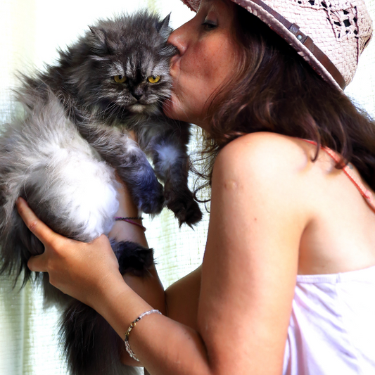 γυναίκα με καπέλο φιλά τη γάτα της